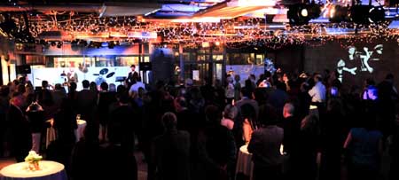 Interior wide shot: Patricia Lynch speaks from the stage with Ben Baldwin and Friends at The Loft